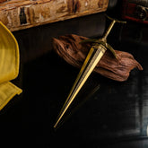 Top-down view of the Golden Order Greatsword replica, highlighting the gold blade against dark wood and yellow silk.