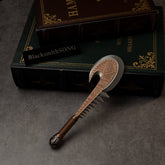 Patu replica (15cm die-cast zinc alloy war club) — toothed, bronze-toned club beside stacked books, by BlacksmithSONG.