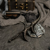 Full view of the Black Knife dagger replica on dark textured ground, surrounded by a moon prop and a wooden chest.