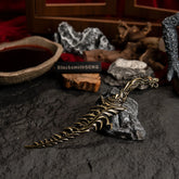 Reduvia metal dagger resting on grey rocks with a red fabric background and wooden props.