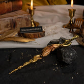 High-angle view of the Greatsword of Damnation on a textured dark surface with a white cloth and candle background.