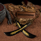 A pair of Starscourge Greatsword metal replicas crossed over each other on red sand. The diorama includes dark rocks, an abandoned mini sword, and a clawed statue piece.