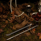Thranduil's Sword metal replica unsheathed on moss, surrounded by old logs, a pearl necklace, and a silver goblet.