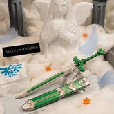 The metallic green Goddess Sword and scabbard displayed on white cotton clouds, with a Goddess Statue, blue feathers, and orange gratitude crystals.