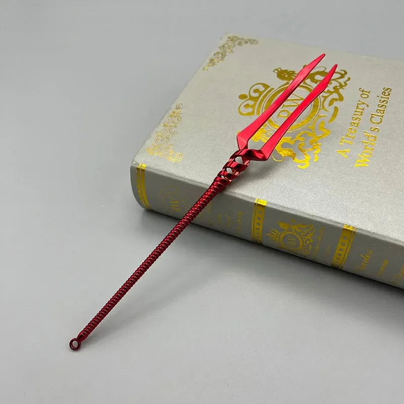 Red zinc alloy anime-style miniature trident on a decorative book, collectible cosplay weapon
