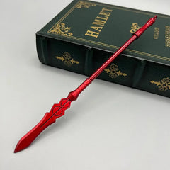 Red zinc alloy anime-style spear replica displayed on a Hamlet book, collectible weapon