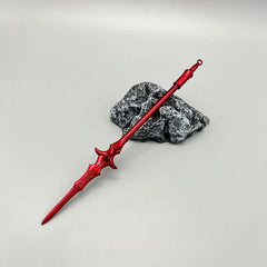 Red anime-style zinc alloy spear replica displayed on a rock, collectible cosplay weapon.