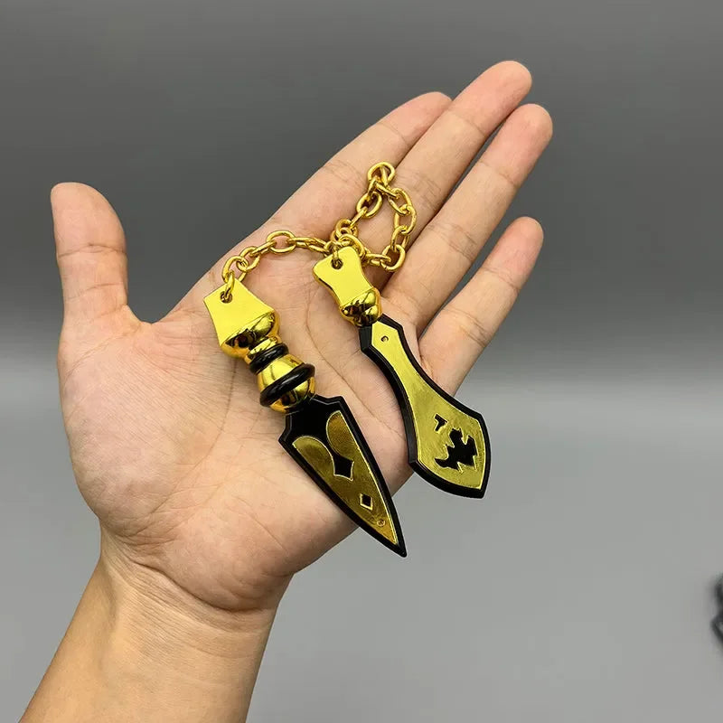 Hand holding two gold and black 1:6 scale anime-style zinc alloy weapon replicas on a chain.