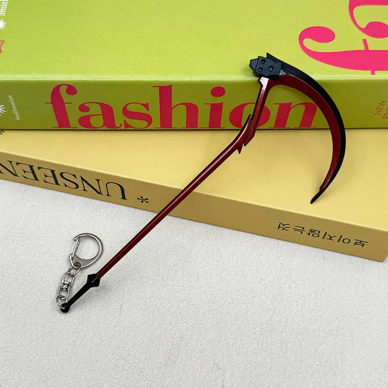 Anime-style zinc alloy scythe keychain replica on books, BlacksmithSONG collectible.