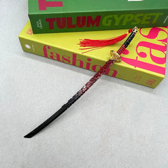 Anime-style zinc alloy katana replica with red tassel on books, BlacksmithSONG collectible.