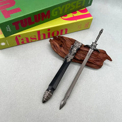 Two anime-style zinc alloy mini sword replicas on wood, with books in background, BlacksmithSONG display collectible.