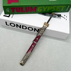 Anime-style zinc alloy sword replica with ornate red sheath on books, BlacksmithSONG collectible.