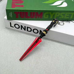 Anime-style zinc alloy red and black weapon replica keychain on books, BlacksmithSONG collectible.