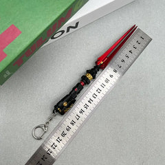 1:6 scale anime-style zinc alloy red and black weapon replica keychain next to ruler