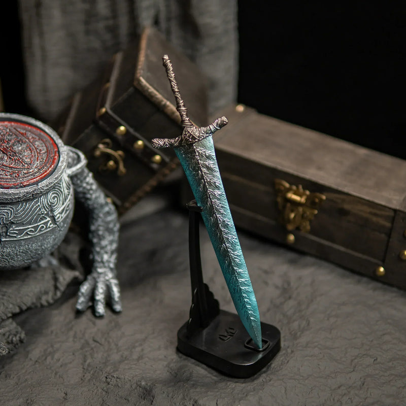 Transform your gaming desk into Ranni’s Rise with this Dark Moon Greatsword metal replica.  Displayed on a custom stand, this Elden Ring sword features stunning frost-blue details and antique weathering. The perfect gaming room accessory or gift for Soulsborne fans.-Vertical display stand