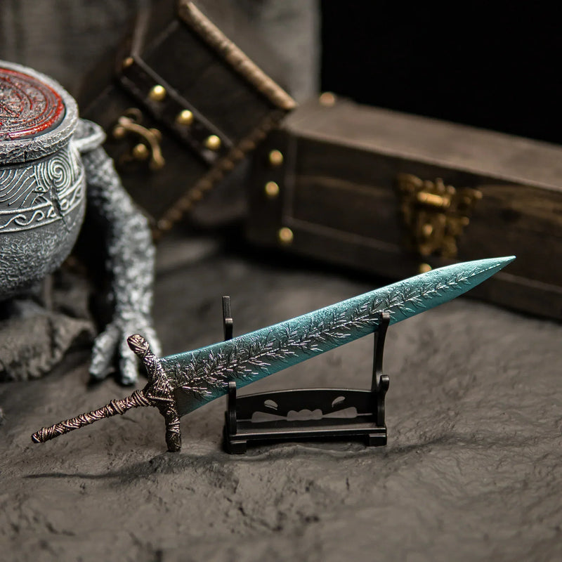 Transform your gaming desk into Ranni’s Rise with this Dark Moon Greatsword metal replica.  Displayed on a custom stand, this Elden Ring sword features stunning frost-blue details and antique weathering. The perfect gaming room accessory or gift for Soulsborne fans.-small display stand