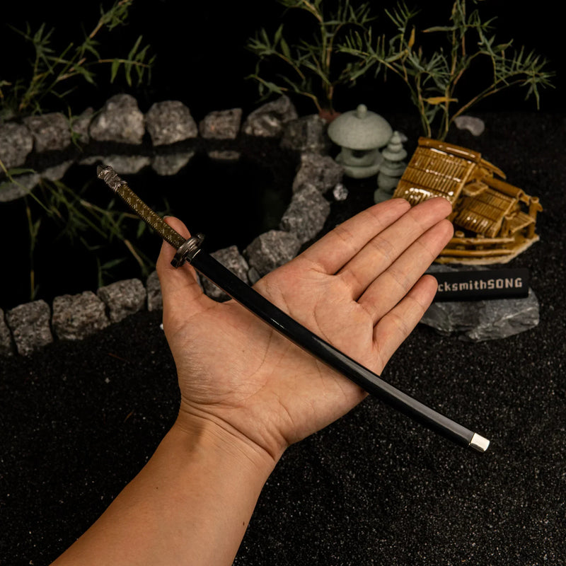 See the Moonveil Katana in its sheath!  This handheld shot shows the realistic 22cm scale of our metal replica. Featuring a glossy black scabbard and detailed hilt, it's a high-quality collectible for Elden Ring fans. Perfect for display or as a small cosplay prop.