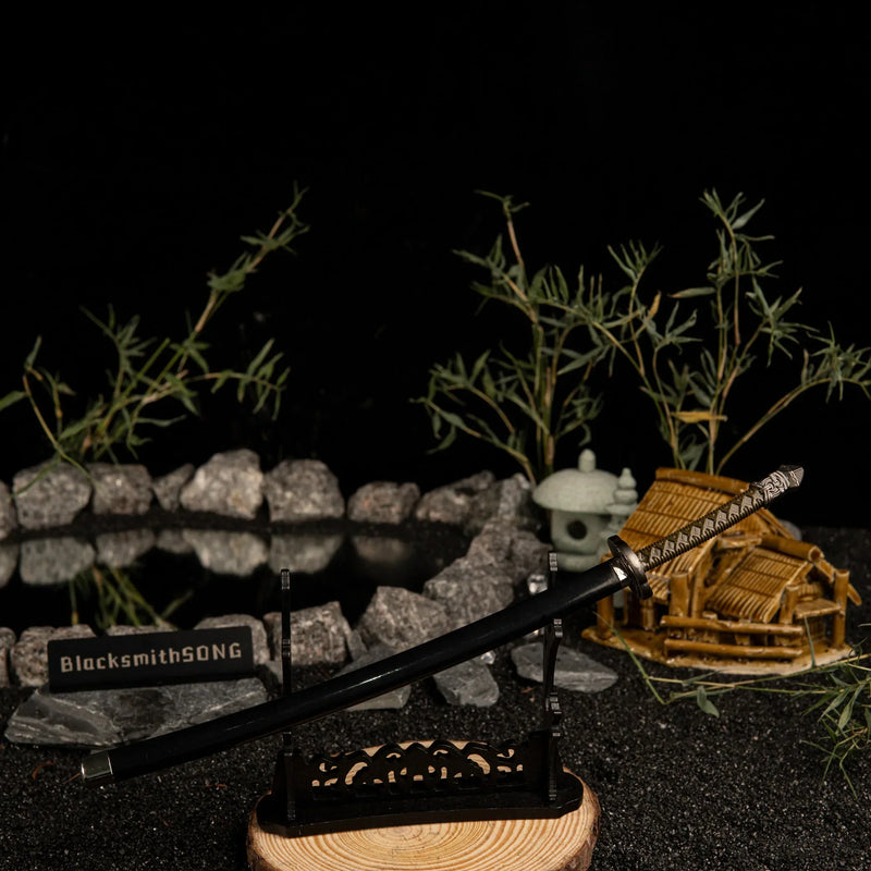 Add a touch of magic to your gaming setup.  This Moonveil Katana metal replica is displayed on a sleek black stand, perfect for a Zen-inspired desk theme. Crafted from zinc alloy, this Elden Ring weapon brings the calm and deadly aesthetic of the Transient Moonlight to your room. - Large display rack