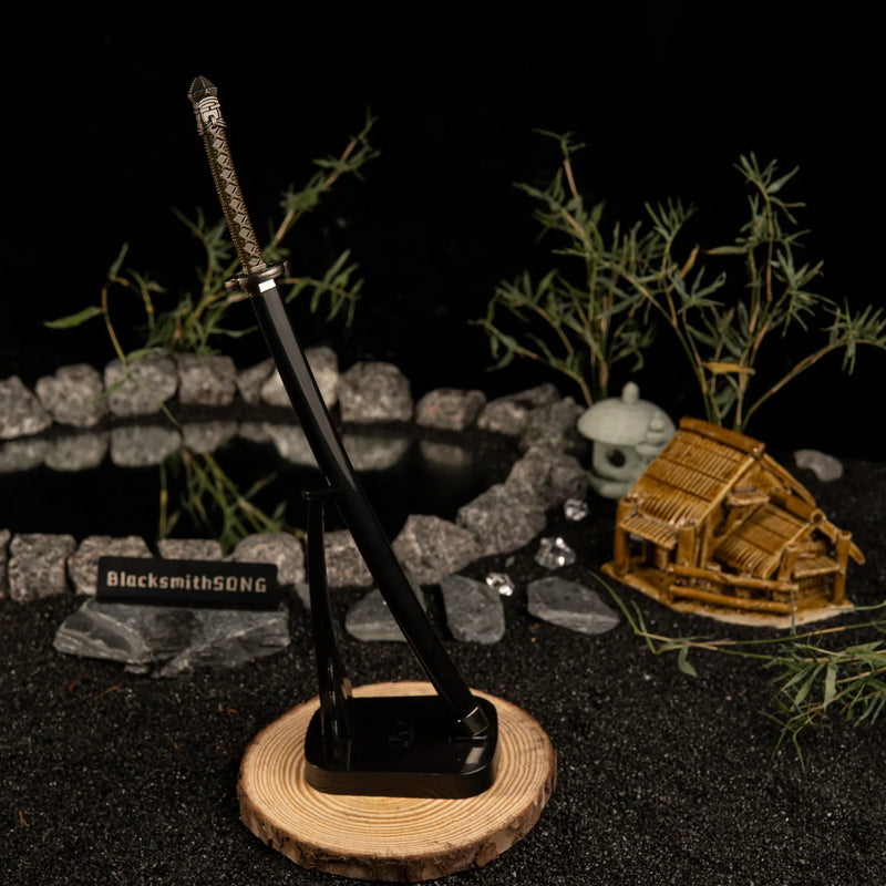 Add a touch of magic to your gaming setup.  This Moonveil Katana metal replica is displayed on a sleek black stand, perfect for a Zen-inspired desk theme. Crafted from zinc alloy, this Elden Ring weapon brings the calm and deadly aesthetic of the Transient Moonlight to your room. - Vertical display rack