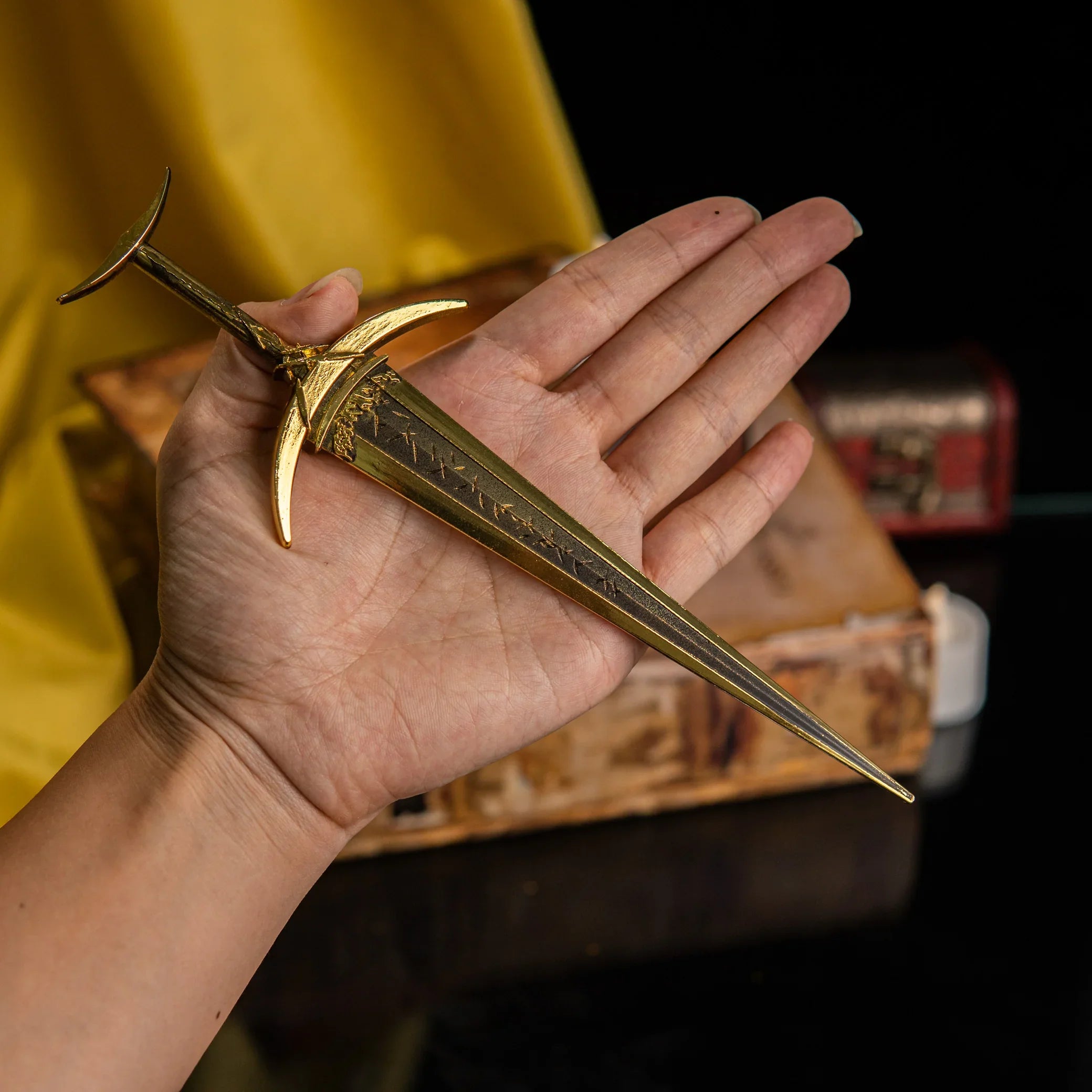 A hand holding the Golden Order Greatsword miniature to show scale.