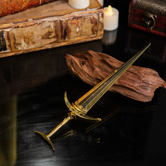 Golden Order Greatsword metal replica displayed on a dark surface with yellow silk fabric in the background.