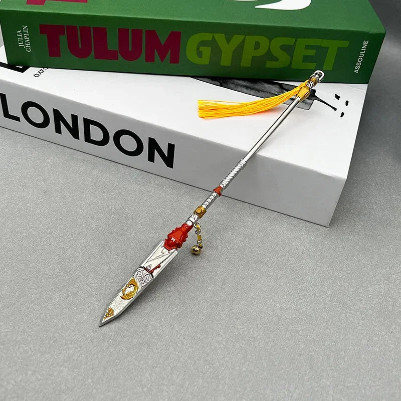 Anime-style zinc alloy spear replica with red accents and yellow tassel, displayed on books