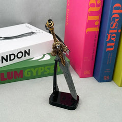 Anime-style zinc alloy collectible sword replica on stand, displayed beside colorful books.