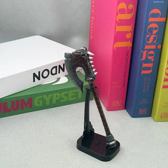 Anime-style zinc alloy axe replica on stand, displayed with colorful books, BlacksmithSONG collectible.