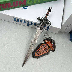 Anime-style zinc alloy sword replica with ornate hilt and sheath keychain on table