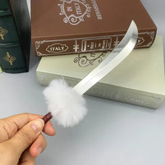 Mini anime-style zinc alloy scimitar replica with fluffy white pompom handle, held by hand