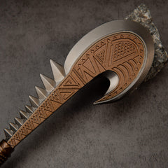Patu replica — close-up of the carved head, silvery rim and triangular teeth.