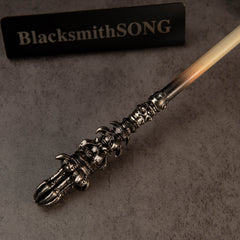 Chitin Staff replica — close-up of the ornate metal end and the cream-colored shaft.