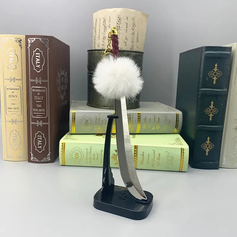 Anime-style zinc alloy sword replica with fluffy white pom, displayed on stand, books in background