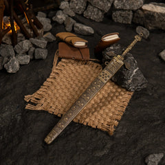 Top-down view of the Banished Knight's Greatsword and scabbard on a textured dark surface with burlap and leather props.
