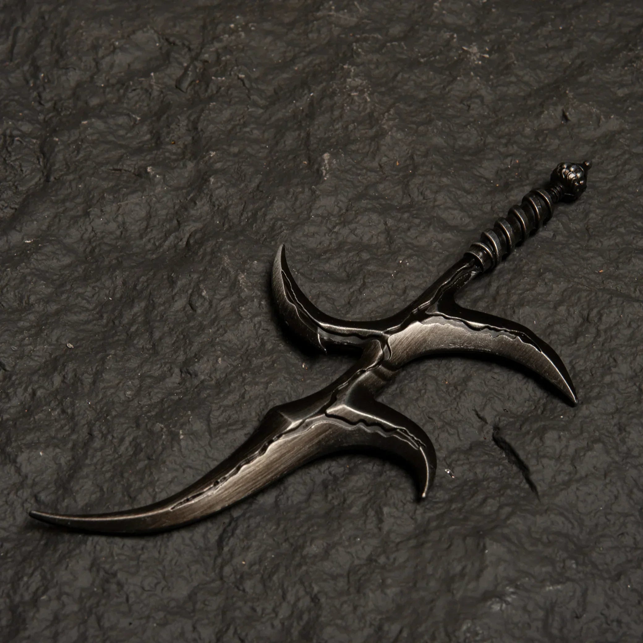 Black Knife metal replica from Elden Ring isolated on a dark grey textured background, showing its warped blade design.
