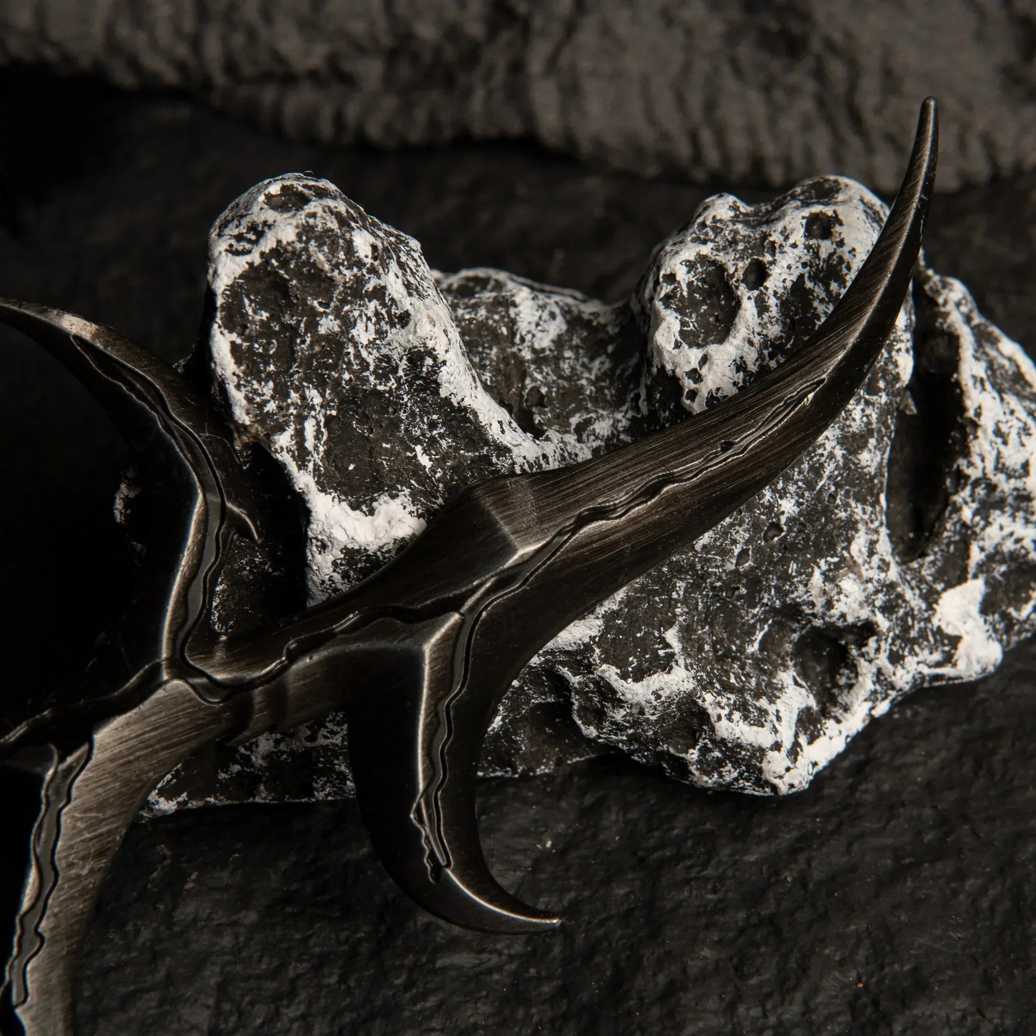 Close-up detail of the Black Knife dagger resting on a white and grey textured rock.