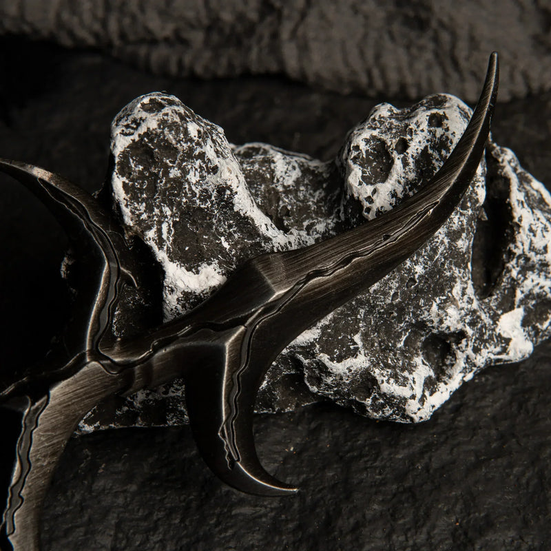Close-up detail of the Black Knife dagger resting on a white and grey textured rock.
