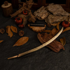 Hand of Malenia replica resting on dark wood surrounded by dry autumn leaves and pinecones.
