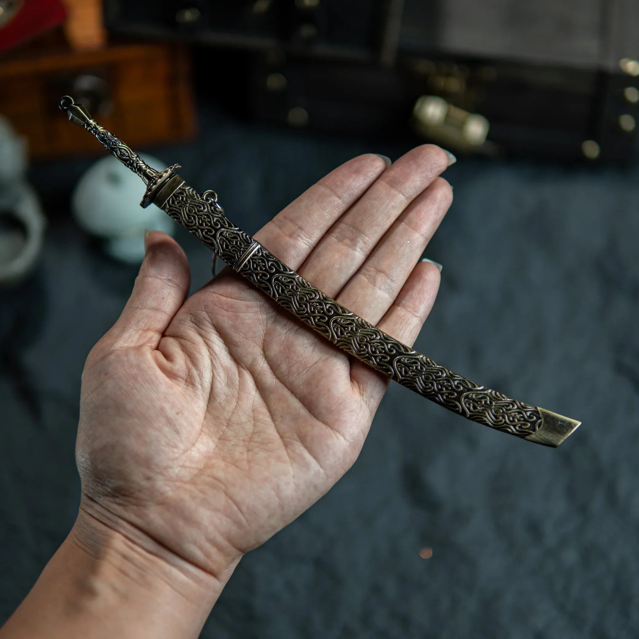 A hand holding the sheathed Meteoric Ore Blade replica, highlighting the scabbard details.