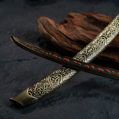 Macro shot of the black katana blade showing red meteoric ore spots and texture.