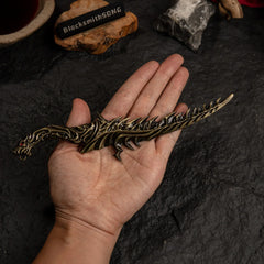 A hand holding the Reduvia dagger replica to show scale. The dagger has a curved, jagged design.