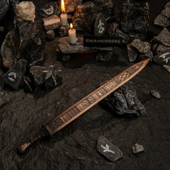 Regalia of Eochaid replica resting on dark rocks marked with white runic symbols, illuminated by candlelight.