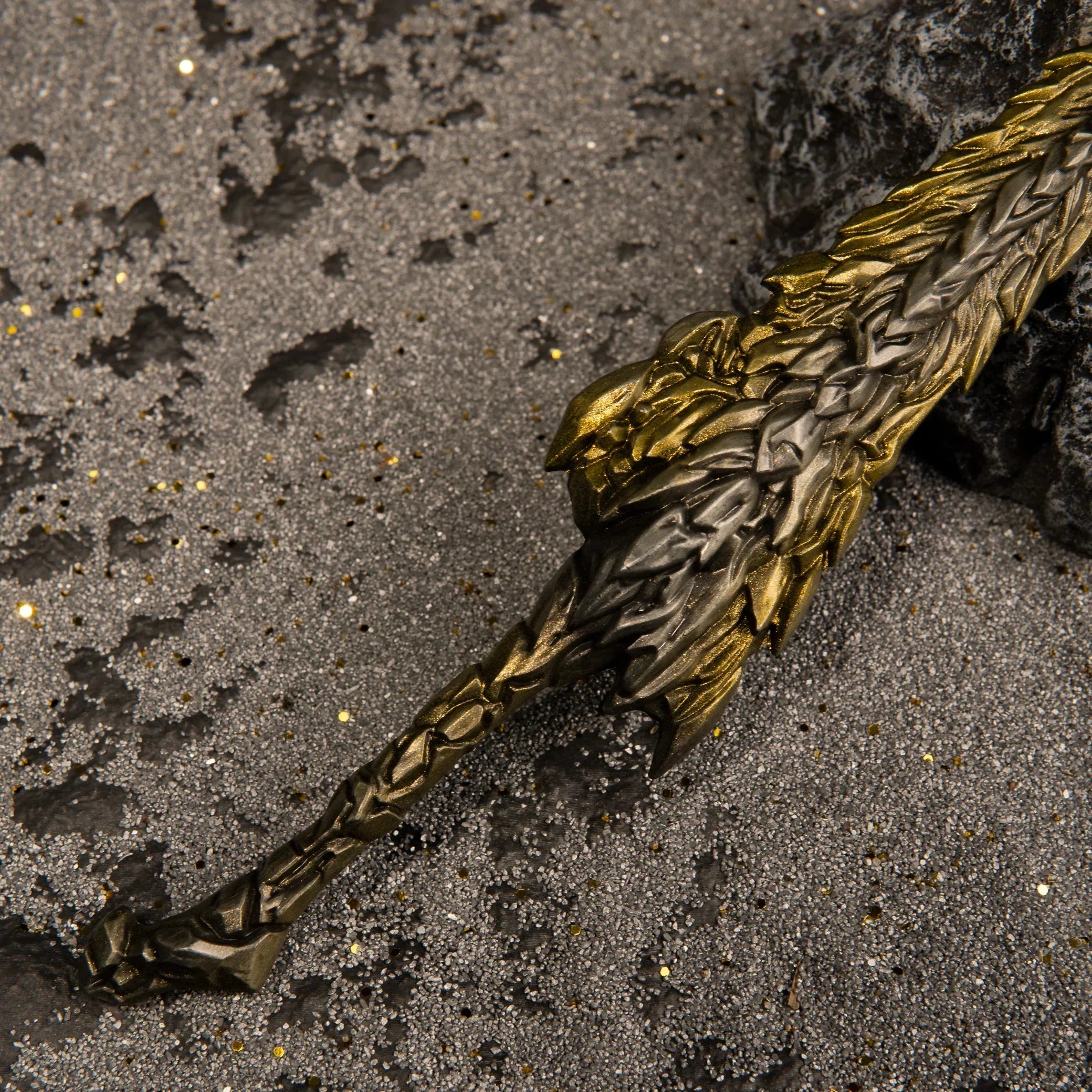 Close-up macro detail of the Dragon King's Cragblade hilt, showing the transition from the dark metal handle to the rough gold blade.