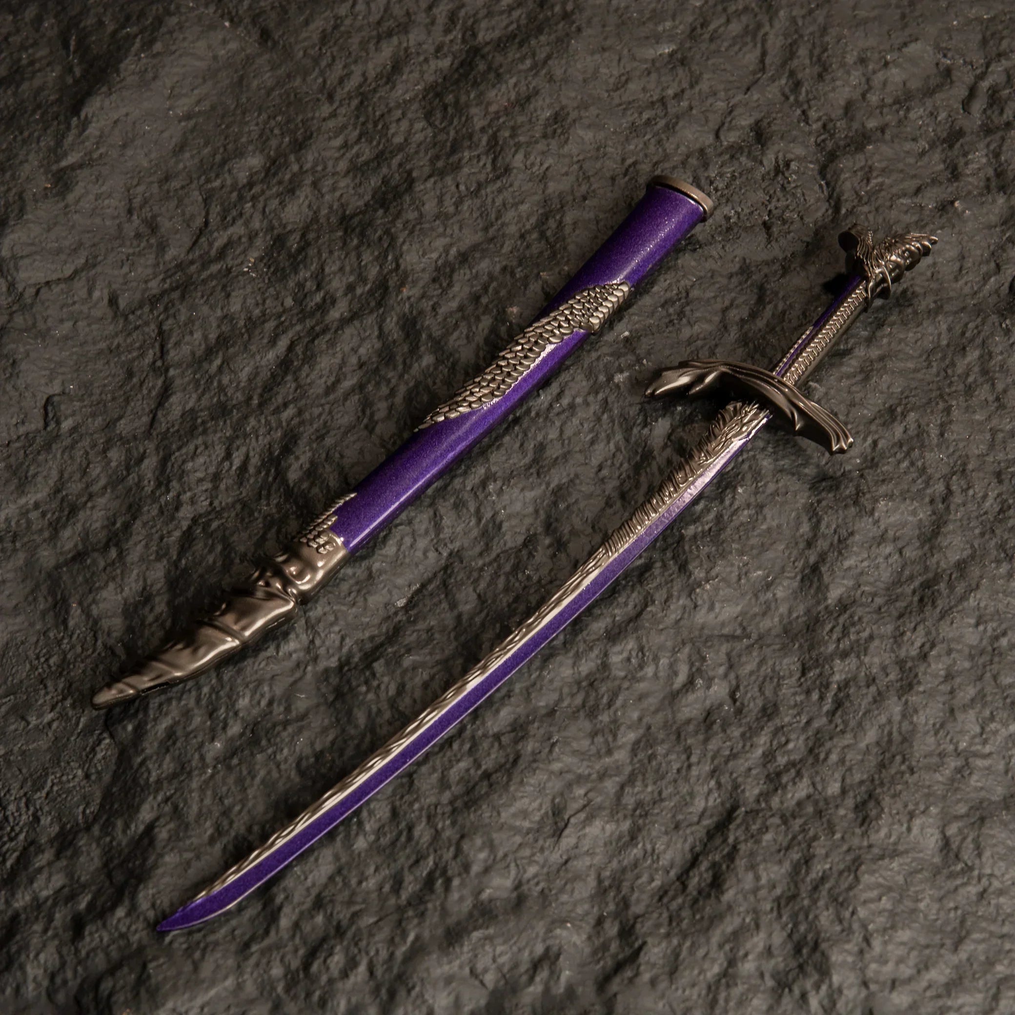 Dragonscale Blade metal katana replica and its purple scabbard isolated on a dark textured background.