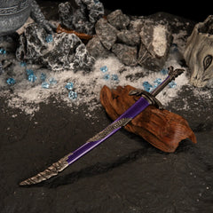 High-angle view of the Dragonscale Blade and its purple scabbard on a dark snowy surface with blue gems and a stone vase prop.