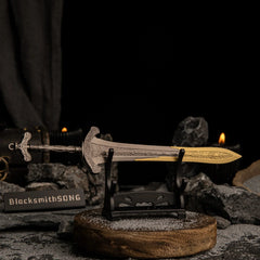 Gargoyle's Greatsword metal replica on a small horizontal display stand, focusing on the hilt and crossguard in a dim environment.