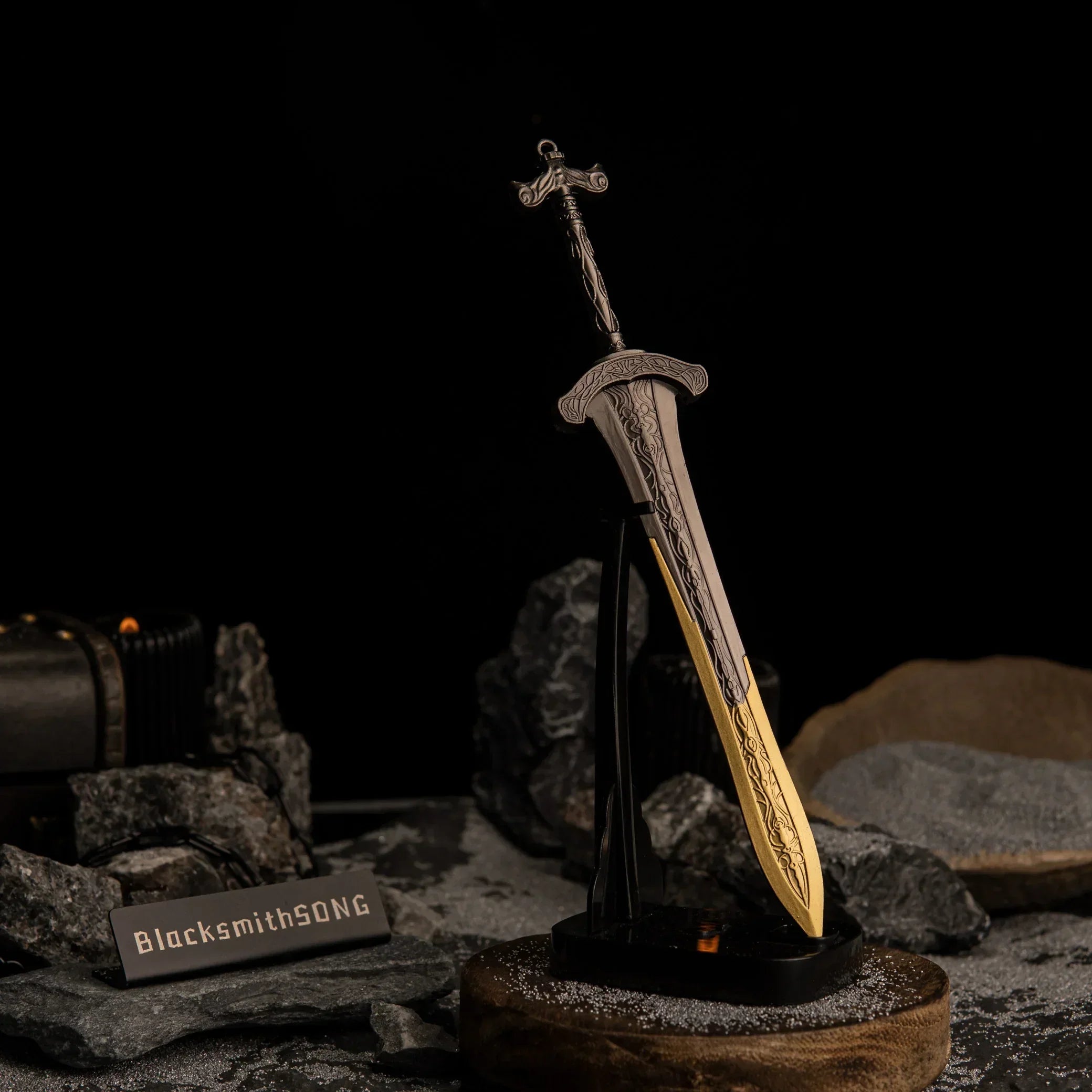 Vertical display of the Gargoyle's Greatsword replica on an upright black stand, set against a dark catacomb aesthetic background with grey sand.