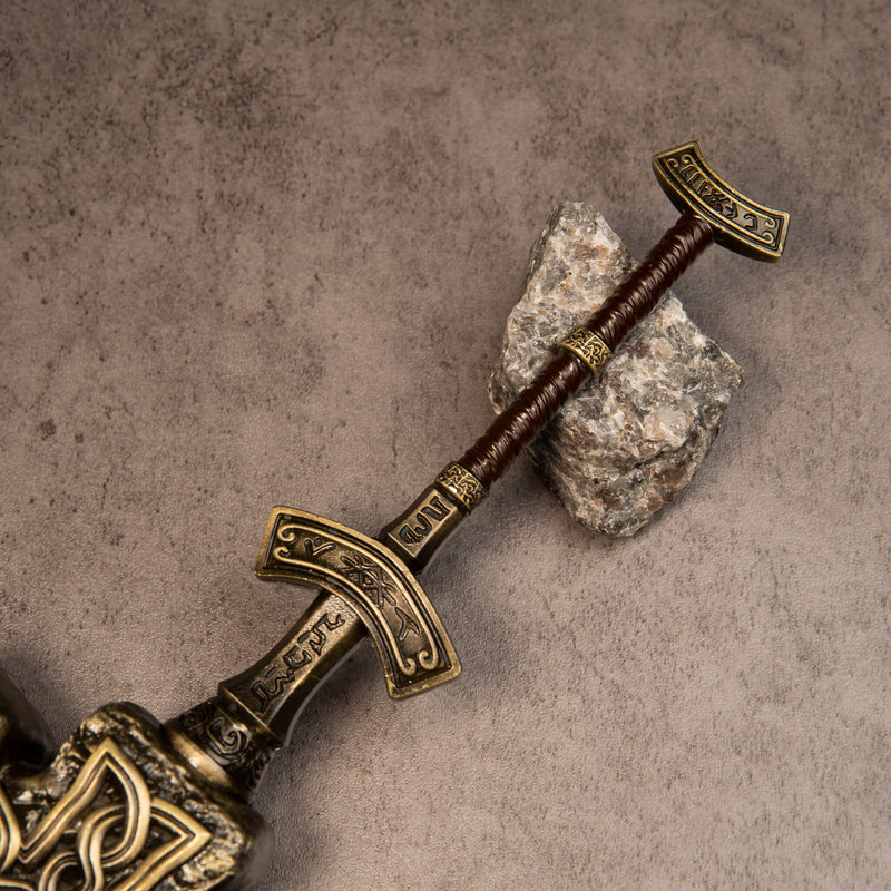 Giant-Crusher replica — grip and pommel resting beside a grey stone.
