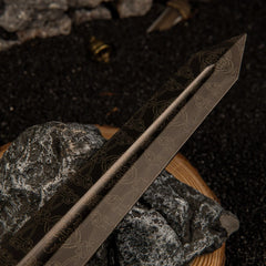 Detailed view of the wide, dark grey metallic blade of the Greatsword replica, showcasing subtle scrollwork engravings along the center fuller.