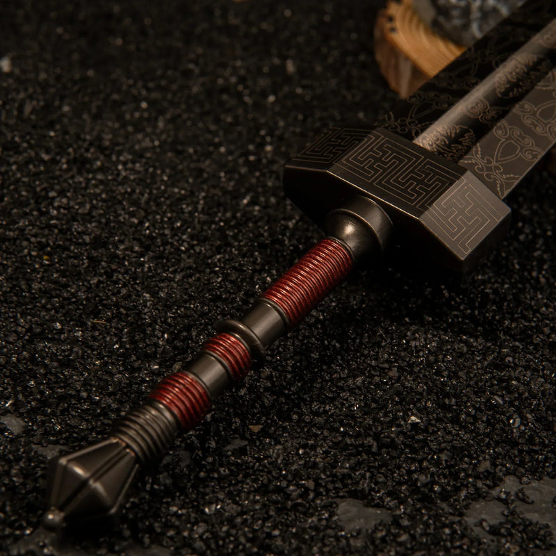 Macro close-up shot of the red-wrapped handle, heavy pommel, and blocky crossguard of the Greatsword metal miniature.